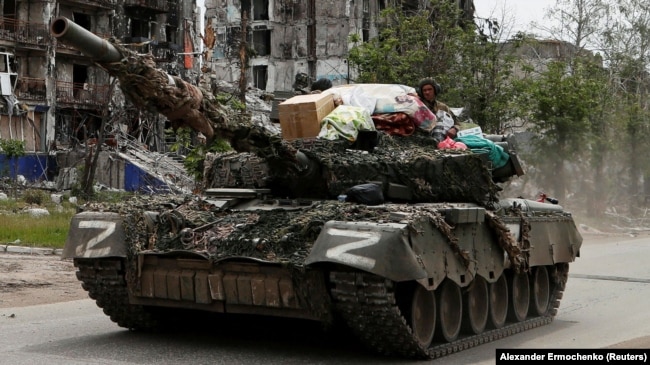 Trupat ruse apo proruse kalojnë me tanke pranë një ndërtese të shkatërruar banimi në qytetin Popasna në rajonin Luhansk, 26 maj 2022.